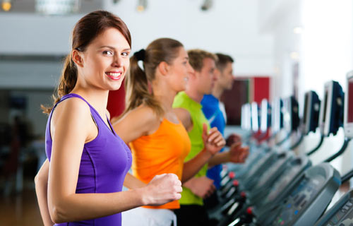 Kvinder der løbetræner på løbebånd i fitness center