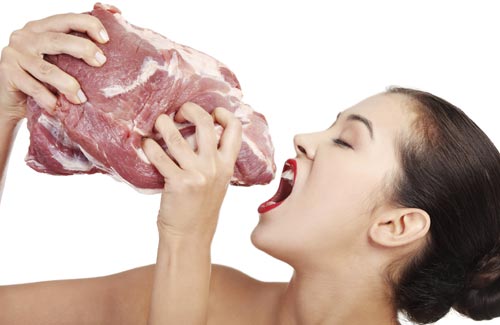 Kvinde der holder en klump råt kød op til munden