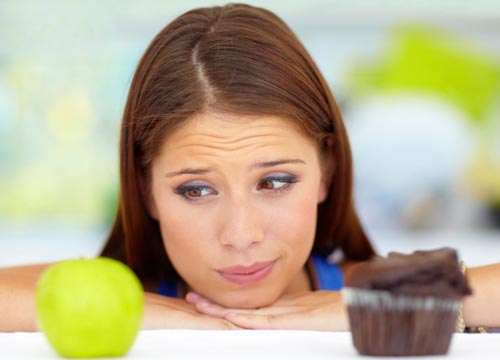 Bekymret kvinde der kigger på et æble og en kage